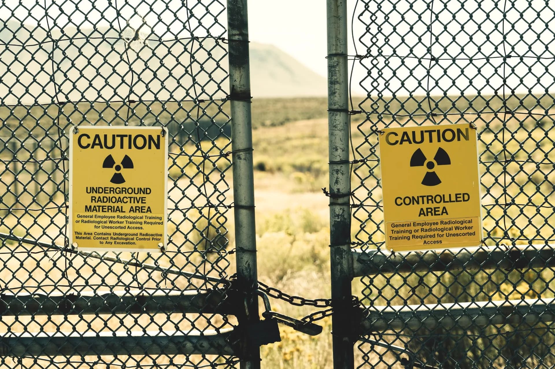 Caution and radioactive warning signs on chain-link fence surrounding a nuclear facility